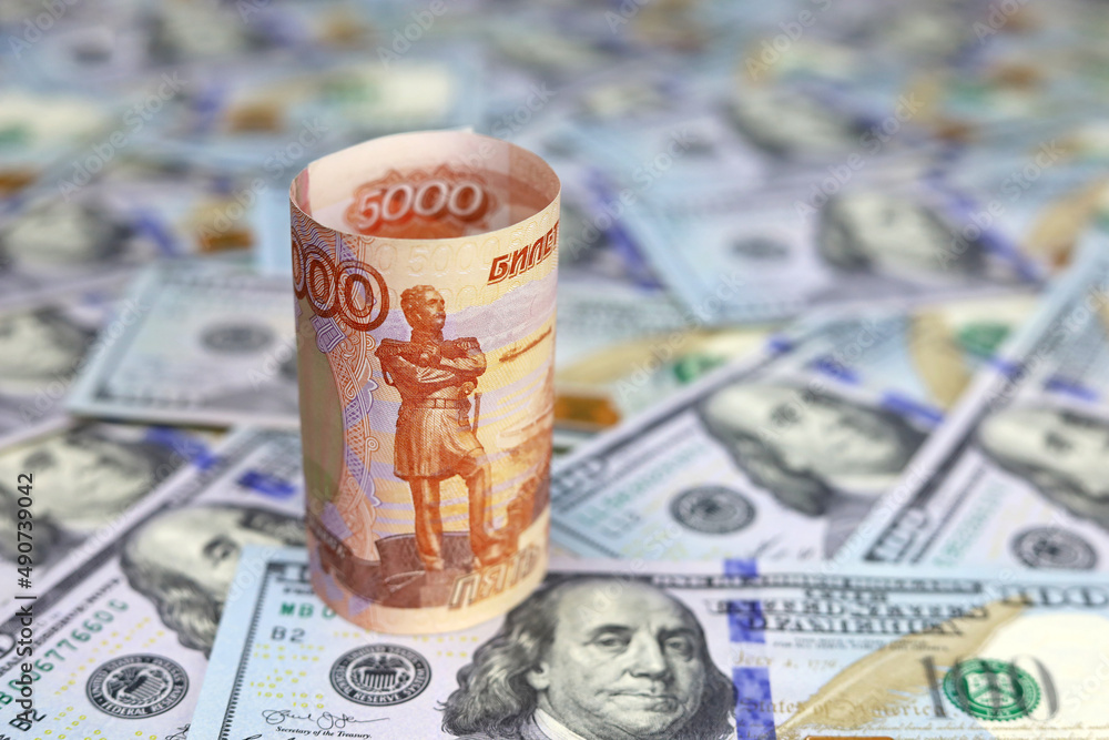 Russian rubles on background of US dollars. Concept of exchange rate, sanctions, falling ruble Russian rubles on background of US dollars. Concept of exchange rate, sanctions, falling ruble