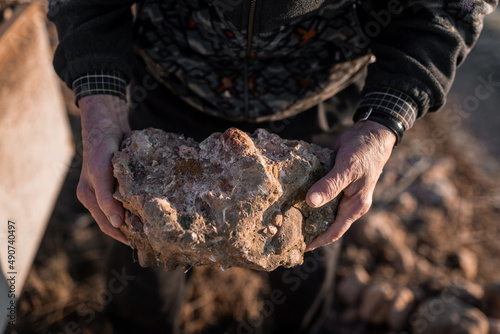 Old man with rough rock in hand photo