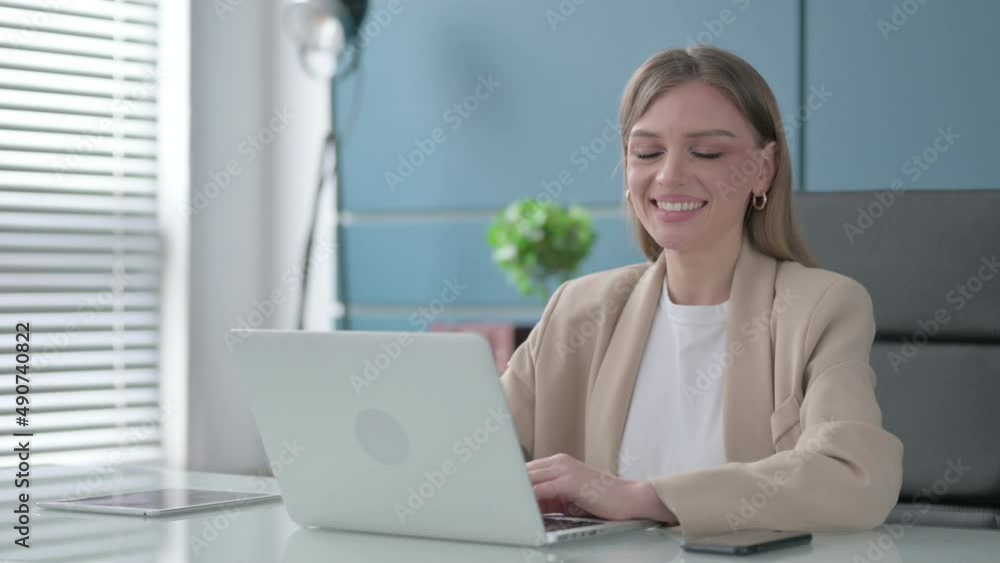 Businesswoman Smiling at Camera while using Laptop in Office Businesswoman Smiling at Camera while using Laptop in Office