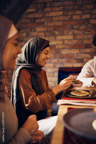 Cheerful Muslim woman enjoys in lunch with her family at home.