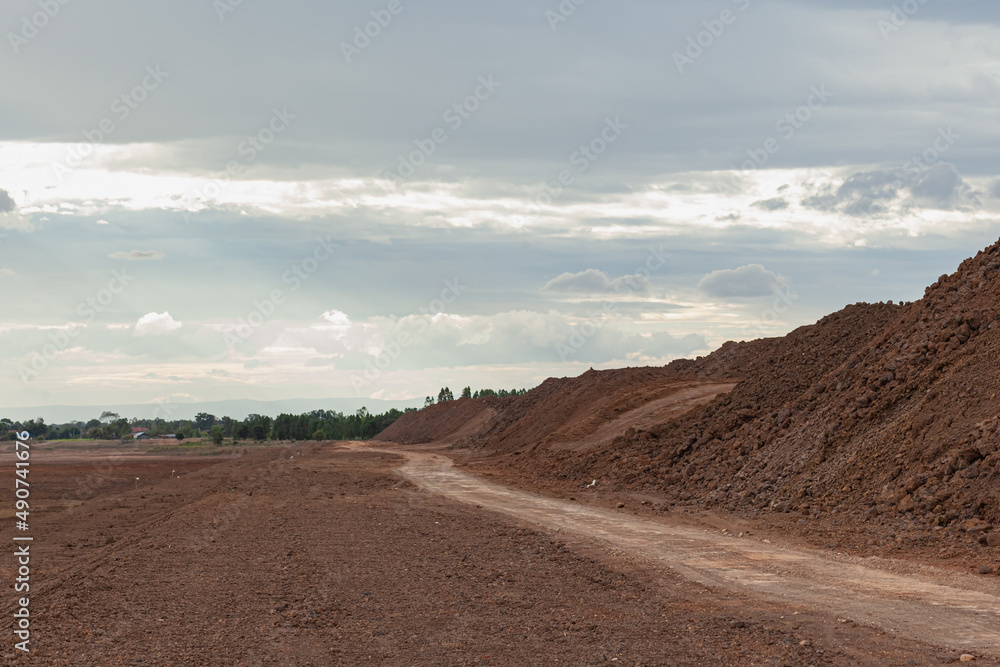 A brown soil path beside a newly excavated reservoir.