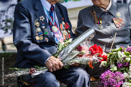 Saying goodbye to a dear friend. Cropped image of two war veterans holding flowers at a funeral. photo