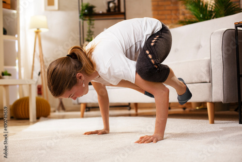 Young woman working out at home. Athletic woman in sportswear doing fitness stretching exercises