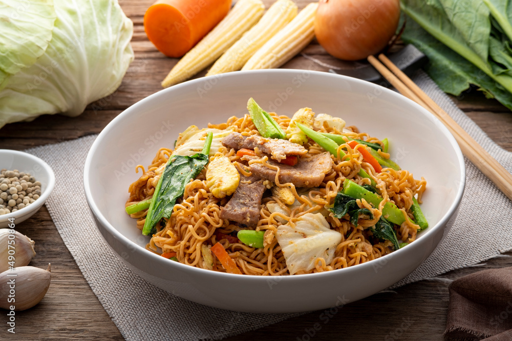 Stir Fried Instant Noodle with pork egg and mixed vegetable on white plate