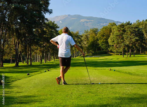 Golfer on a golf course, ready to go. Golfer with golf club on tee, studying for the perfect shot