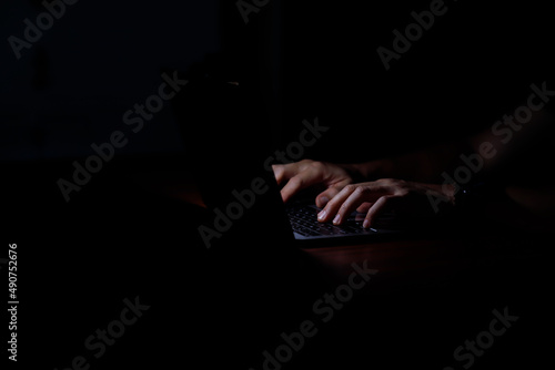 A man hand using laptop computer to hacker hacking the server in the dark, Digital crime by an anonymous hacker