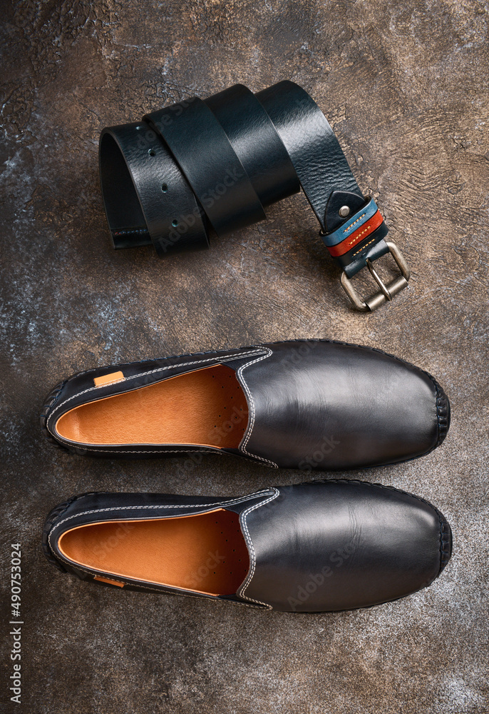 Blue stylish leather mens moccasins and leather pant belt on stone background Blue stylish leather mens moccasins and leather pant belt on stone background