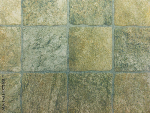 Square stone tile of light brown color with a stone texture and scuffs. Grey vintage background.
