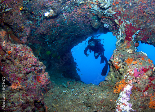 Scuba diver observes a underwater cave in the sea.