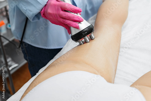 The doctor does the Rf lifting procedure on the legs, buttocks and hips of a woman in a beauty parlor.