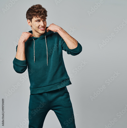 Handsome man wear of green set of track suit isolated on gray background