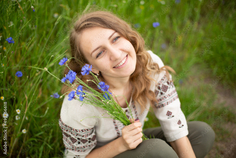 Girl wearing national Ukrainian clothes embroidered shirt is sitting in the beautiful rye field. Woman is holding blue field flowers cornflowers. Blue wildflowers and blond wavy haired girl
Girl wearing national Ukrainian clothes embroidered shirt is sitting in the beautiful rye field. Woman is holding blue field flowers cornflowers. Blue wildflowers and blond wavy haired girl