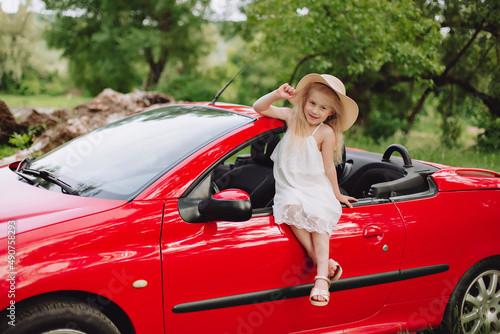 Ukrainian beautiful 7 year old girl on red cabriolet.