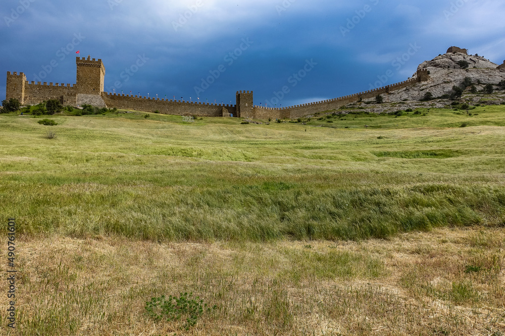 A picturesque view with a stormy sky of the Fortress Mountain and the ancient fortress. Genoese Fortress, Sudak, Crimea A picturesque view with a stormy sky of the Fortress Mountain and the ancient fortress. Genoese Fortress, Sudak, Crimea