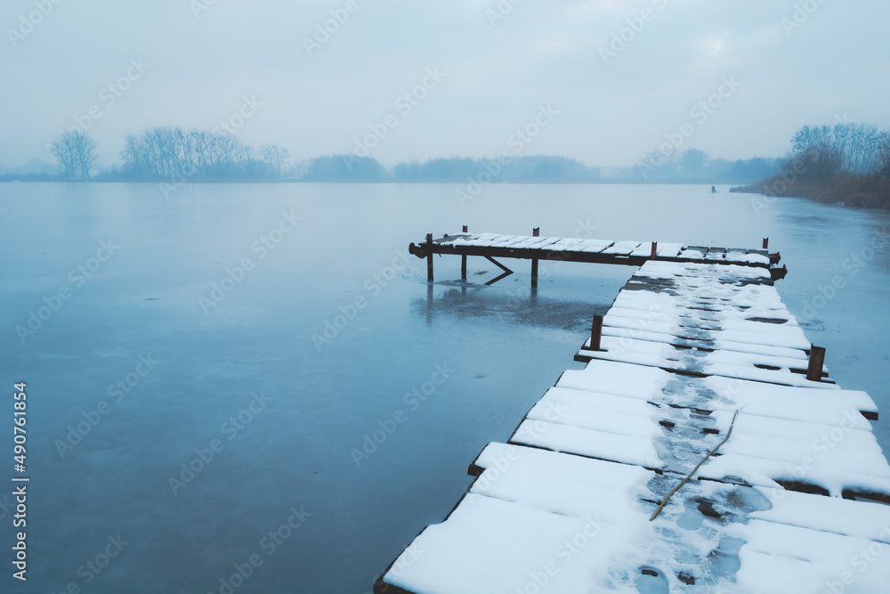A snow-covered wooden pier on a frozen lake