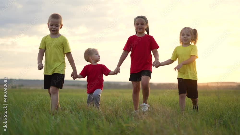 Happy family. Children walk holding hands. Kids play in park on green grass. Children walk in field at sunset. Weekend picnic in nature. Childhood dream concept.Happy family of kids cheerful childhood Happy family. Children walk holding hands. Kids play in park on green grass. Children walk in field at sunset. Weekend picnic in nature. Childhood dream concept.Happy family of kids cheerful childhood