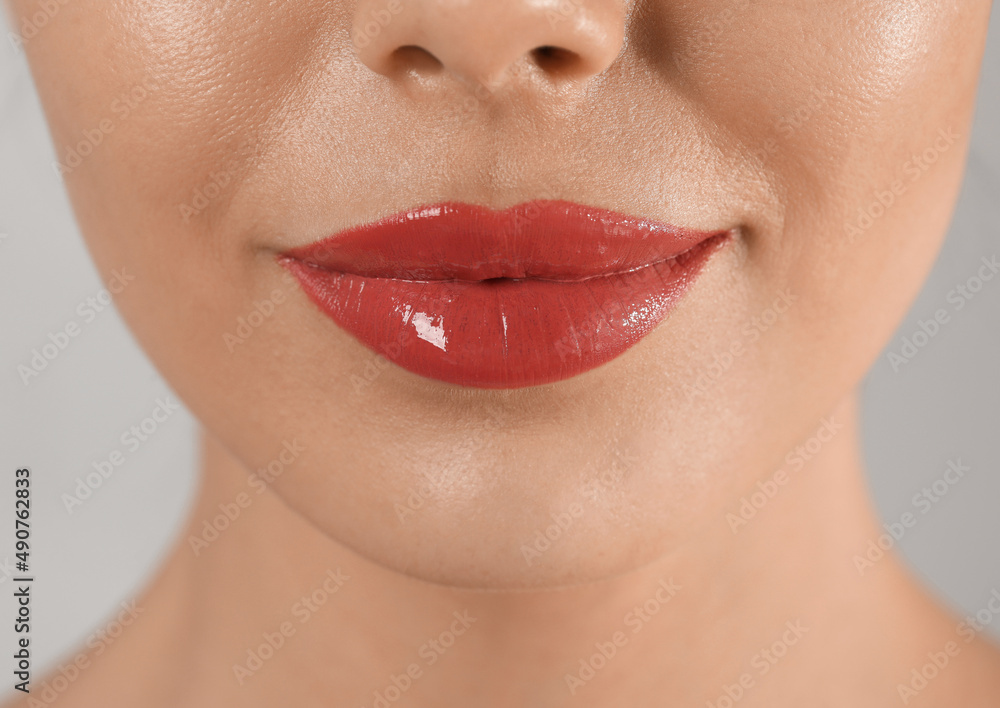 Obraz premium Young woman with permanent lip makeup on grey background, closeup