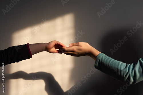 Children's holding hands in shadow against wall indoors