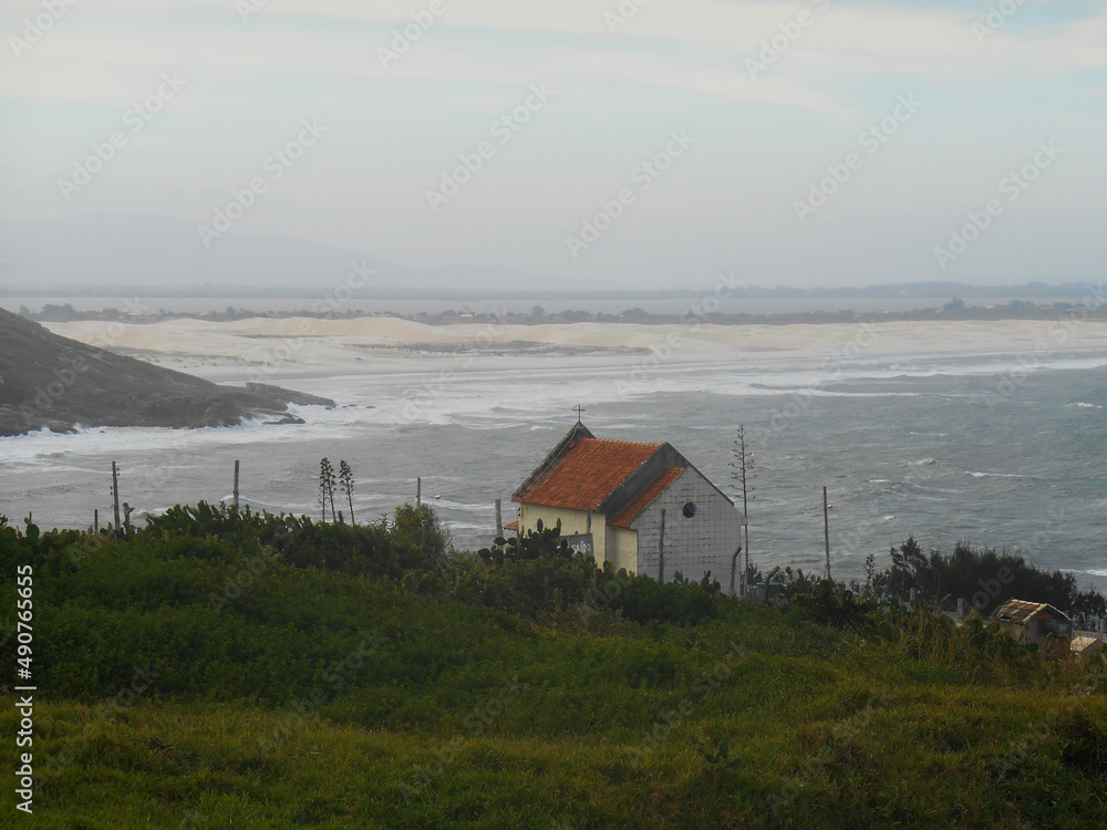 chapel of Santa Marta with green vegetation in the foreground with the dunes of Grande beach, Laguna, SC, Brazil chapel of Santa Marta with green vegetation in the foreground with the dunes of Grande beach, Laguna, SC, Brazil