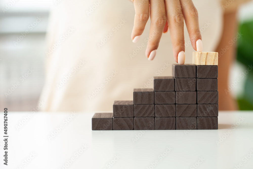 Female fingers climb ladder made of wooden blocks Female fingers climb ladder made of wooden blocks