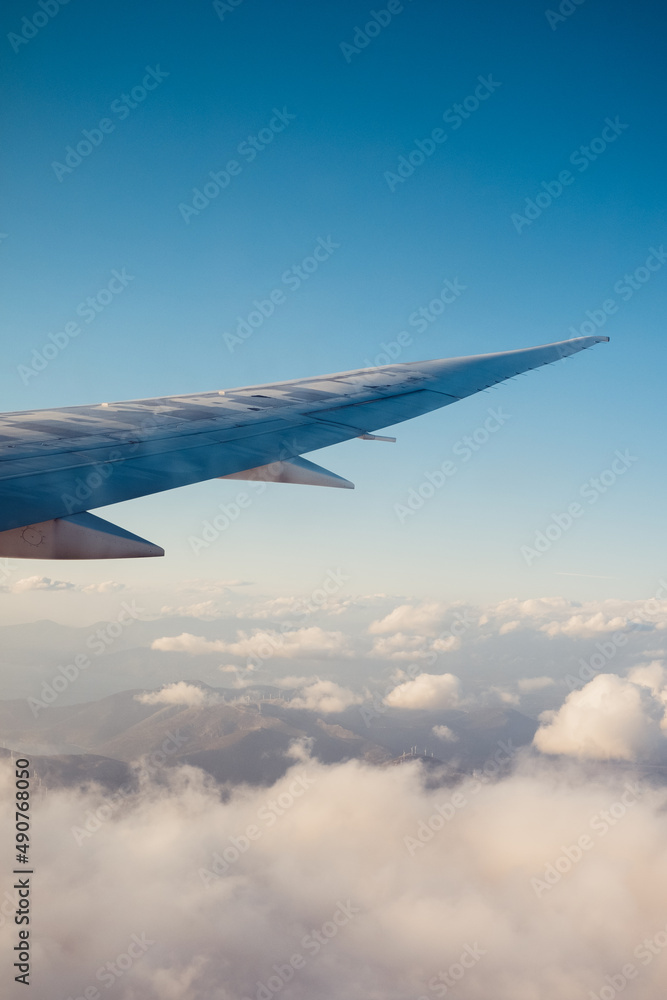 Obraz premium Flugzeugflügel über den Wolken im Hochformat