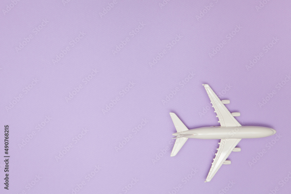 Airplane model. White plane on purple background. Travel vacation concept. Summer background. Flat lay.