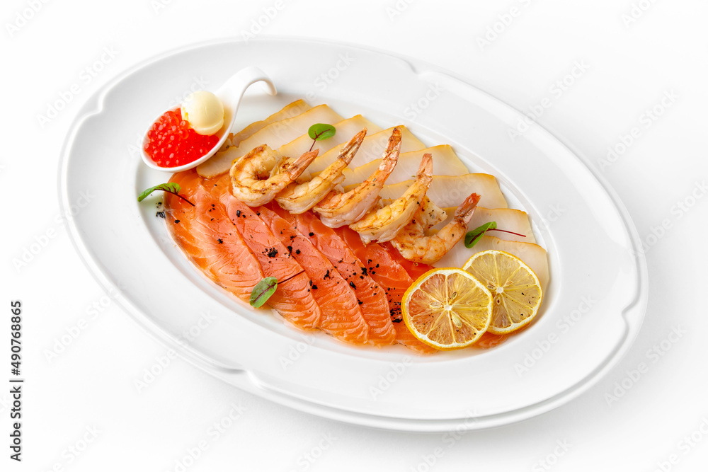 Plate with appetizer of fish and seafood. Sliced salted fish fillet. Smoked salmon, perch, prawn. Banquet festive dishes. Gourmet restaurant menu. White background. Plate with appetizer of fish and seafood. Sliced salted fish fillet. Smoked salmon, perch, prawn. Banquet festive dishes. Gourmet restaurant menu. White background.