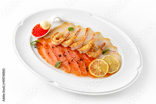 Plate with appetizer of fish and seafood. Sliced salted fish fillet. Smoked salmon, perch, prawn. Banquet festive dishes. Gourmet restaurant menu. White background.
