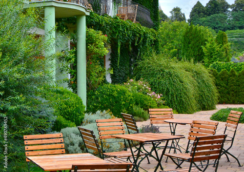 kącik wypoczynkowy wśród zieleni, drewniane krzesła i stoliki, meble ogrodowe na patio, wooden garden furniture, lounge furniture on the garden patio