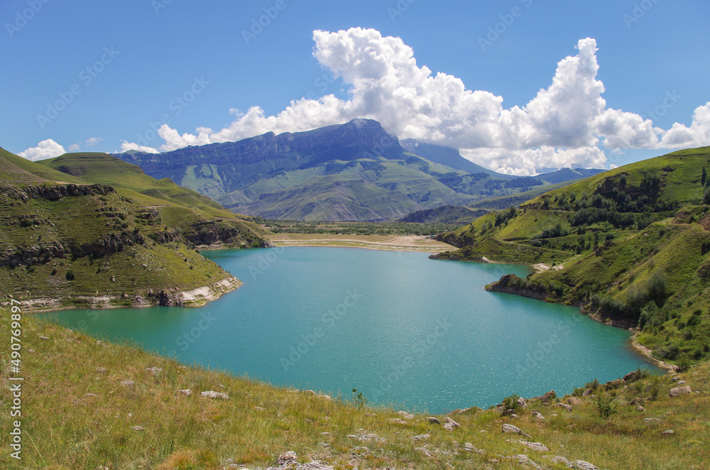Sunny day on the shore of lake. Lake Gizhgit with special green-blue color water. Nature and travel. Russia, Caucasus, Kabardino-Balkaria