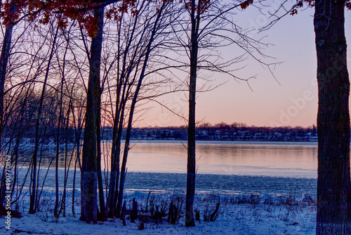 Tranquil landscape at the beginning of winter with the river partly frozen and bare trees