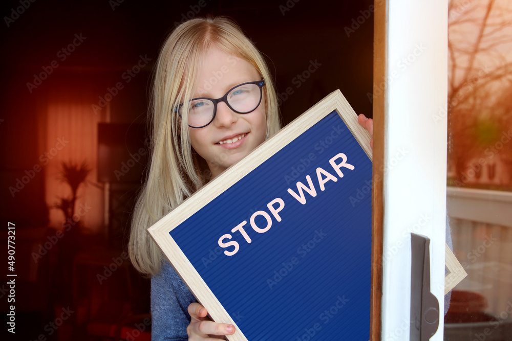 Beautiful girl stays near the open window with banner STOP WAR. Beautiful girl stays near the open window with banner STOP WAR.