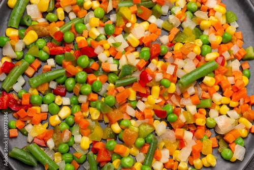 Vegetable mix of carrots, corn, asparagus on black plate.