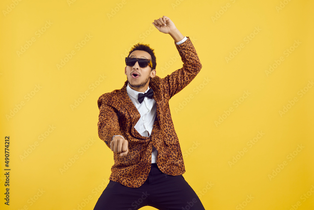 © Studio Romantic - Happy funny positive young black man dancing gangnam style isolated on a yellow colour background. Studio shot of a handsome goofy African guy in a leopard party jacket dancing to k pop music © Studio Romantic - Happy funny positive young black man dancing gangnam style isolated on a yellow colour background. Studio shot of a handsome goofy African guy in a leopard party jacket dancing to k pop music
