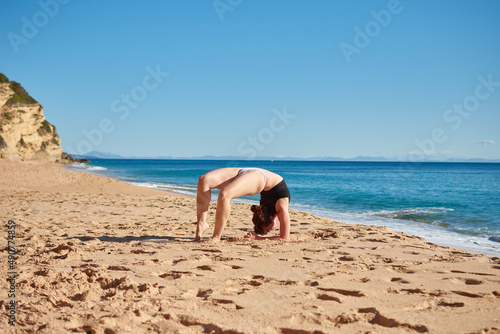 A closeup of a young woman doing a yoga on the beach