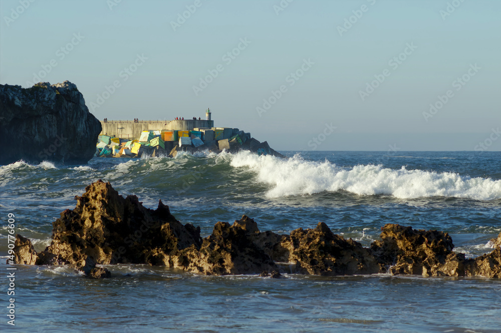 waves breaking against the decorated breakwater of Llanes