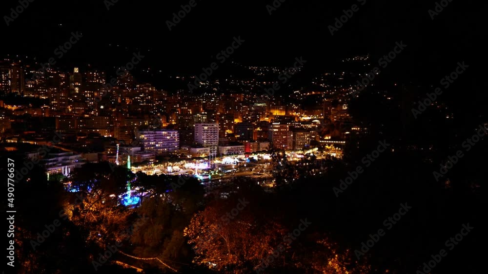 Panoramic view of the illuminated downtown of Monaco at night with colorful funfair and marina Port Hercule surrounded by buildings. Panoramic view of the illuminated downtown of Monaco at night with colorful funfair and marina Port Hercule surrounded by buildings.