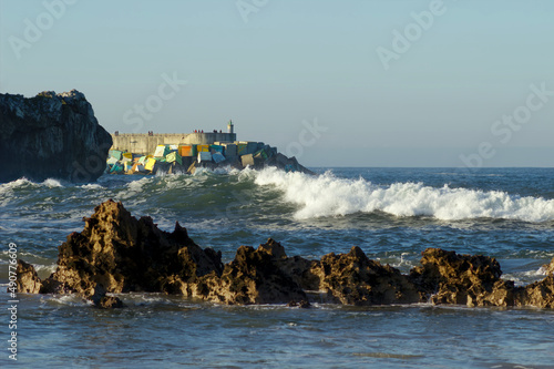 waves breaking against the decorated breakwater of Llanes