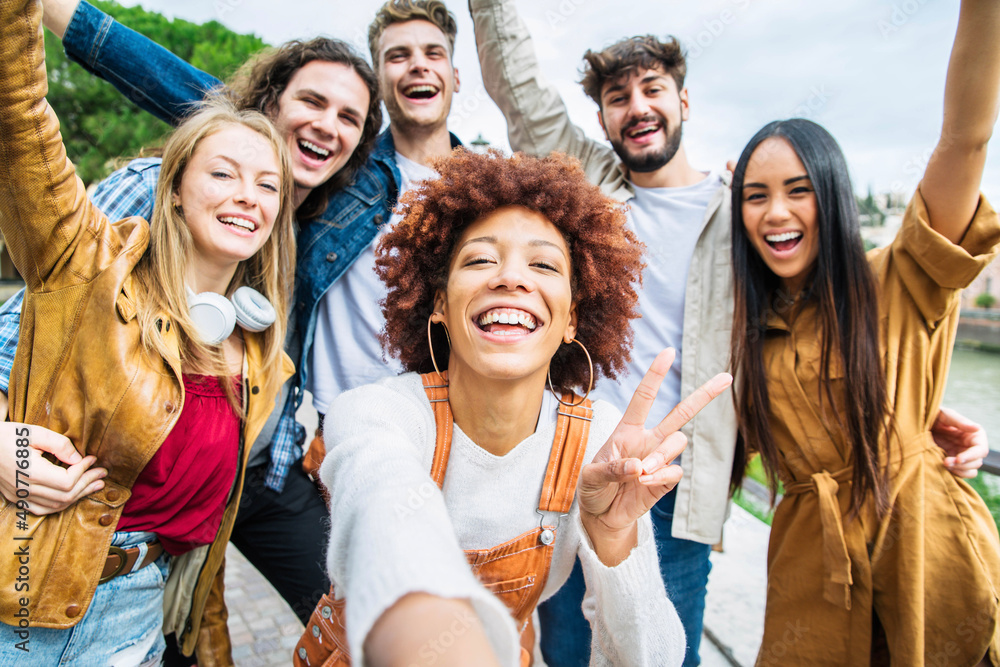 Obraz premium Multiracial group of friends taking selfie pic outside - Happy different young people having fun walking in city center - Youth lifestyle concept with guys and girls enjoying day out together