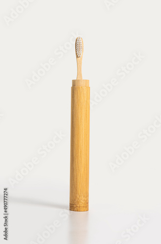 An upright bamboo toothbrush on a light background. A zero-waste or low-waste alternative to plastic.