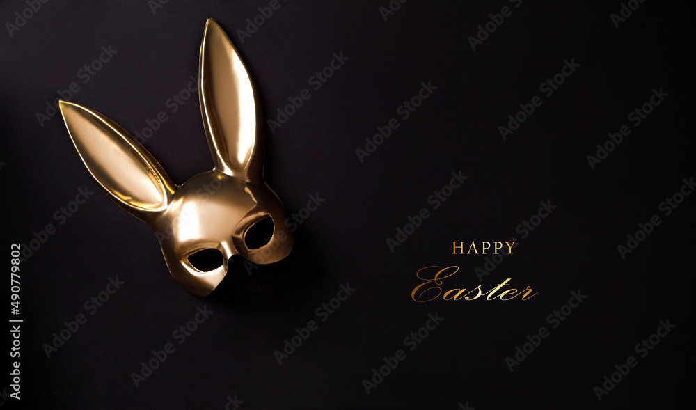 Easter background with gold bunny mask decor. Top view with copy space. Minimalism. Happy Easter. Gold mask on black background.