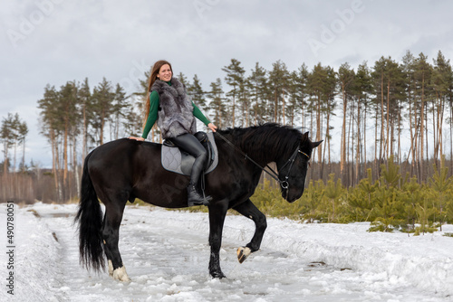 Girl with red hair riding a horse. Winter walk with your beloved pet