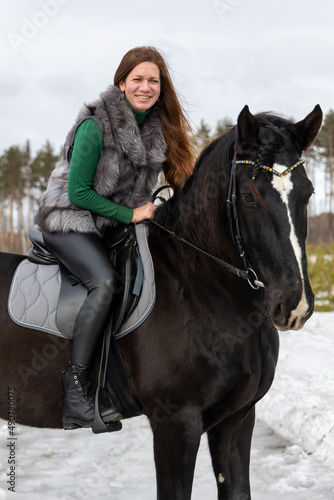 Girl with red hair riding a horse. Winter walk with your beloved pet © Galina