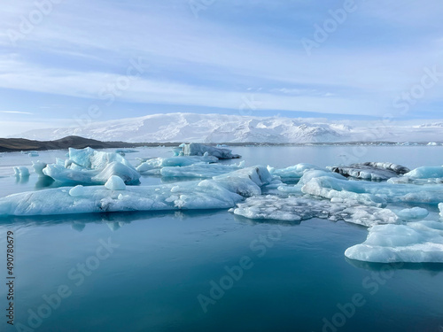 Icy coastal landscape in Iceland, full of big pieces of ice on the beach and floating in the water. 