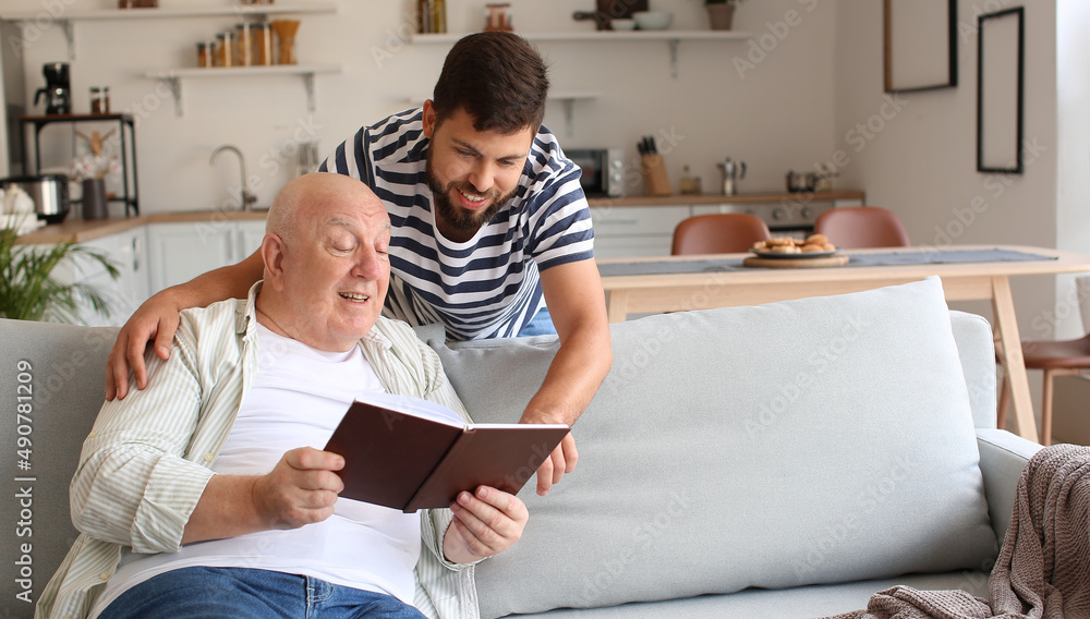 Man and his senior father reading book at home Man and his senior father reading book at home