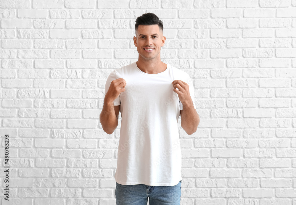 Handsome young man in stylish t-shirt on white brick background Handsome young man in stylish t-shirt on white brick background