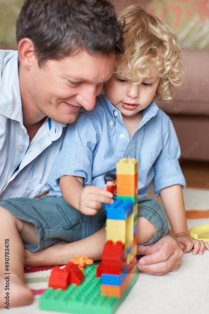 Hes a brilliant builder just like his dad. A father watching his toddler son playing with building blocks. Hes a brilliant builder just like his dad. A father watching his toddler son playing with building blocks.