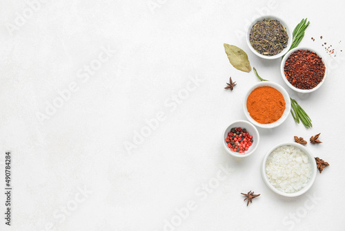 Composition with bowls of aromatic spices and herbs on light background