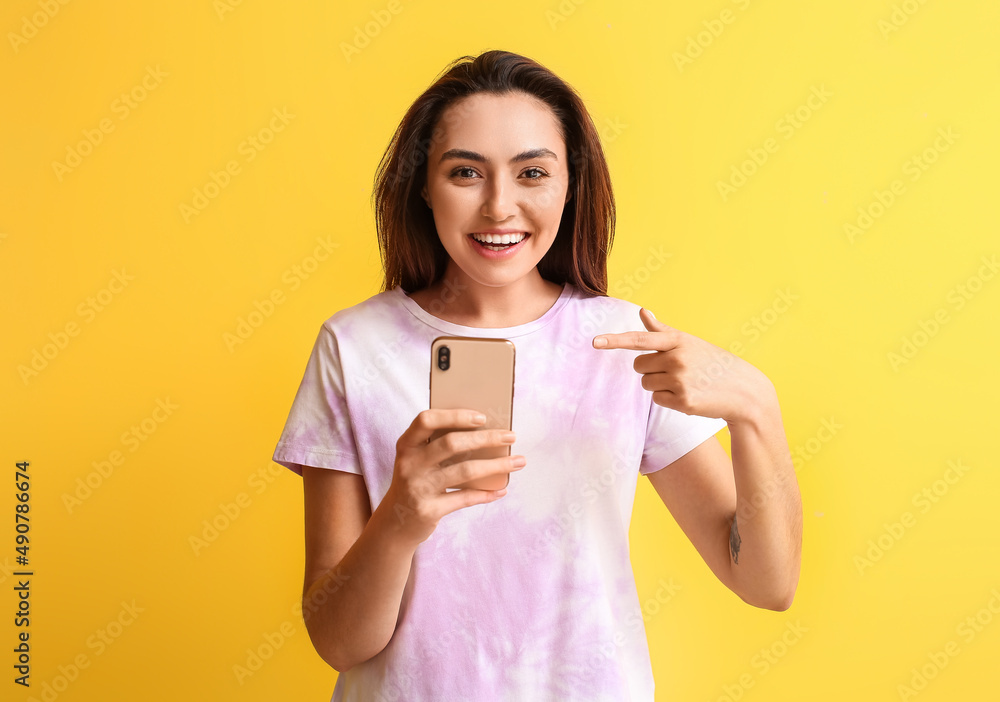 Smiling woman pointing at mobile phone on yellow background. E-mail concept Smiling woman pointing at mobile phone on yellow background. E-mail concept