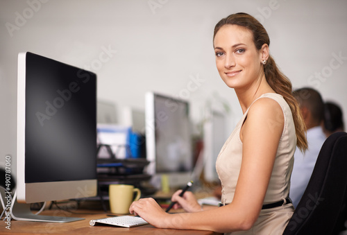 Enjoying her work environment. Portrait of an attractive young office worker at her computer.